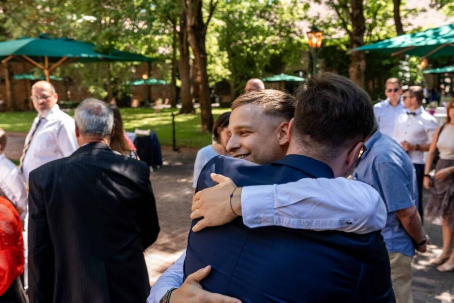 Gäste umarmen sich im Garten, Sommerhochzeit. Hofgut Hünersdorff