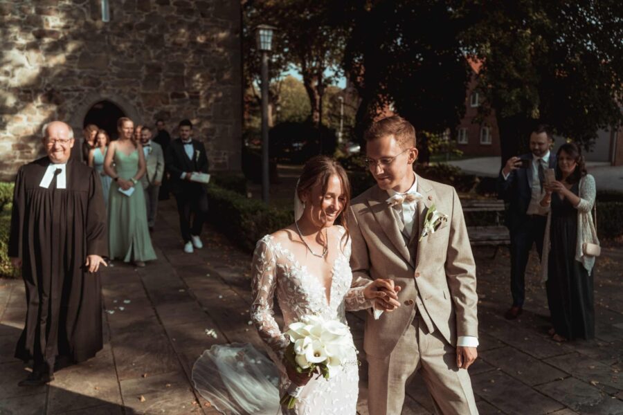 Brautpaar verlässt Kirche mit Blumenstrauß