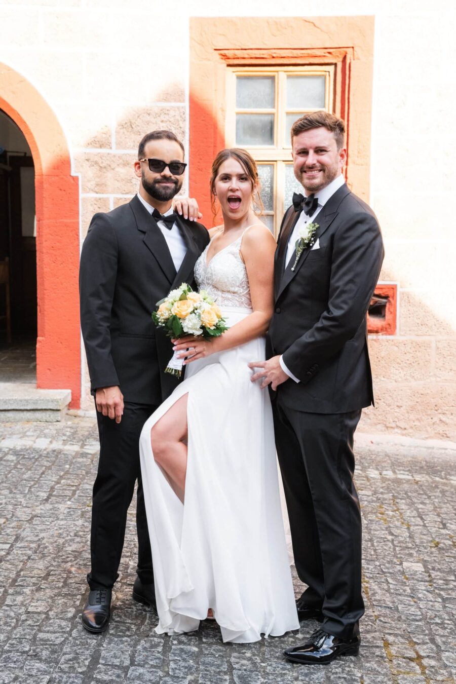 Brautpaar und Trauzeuge vor Backsteinkulisse
