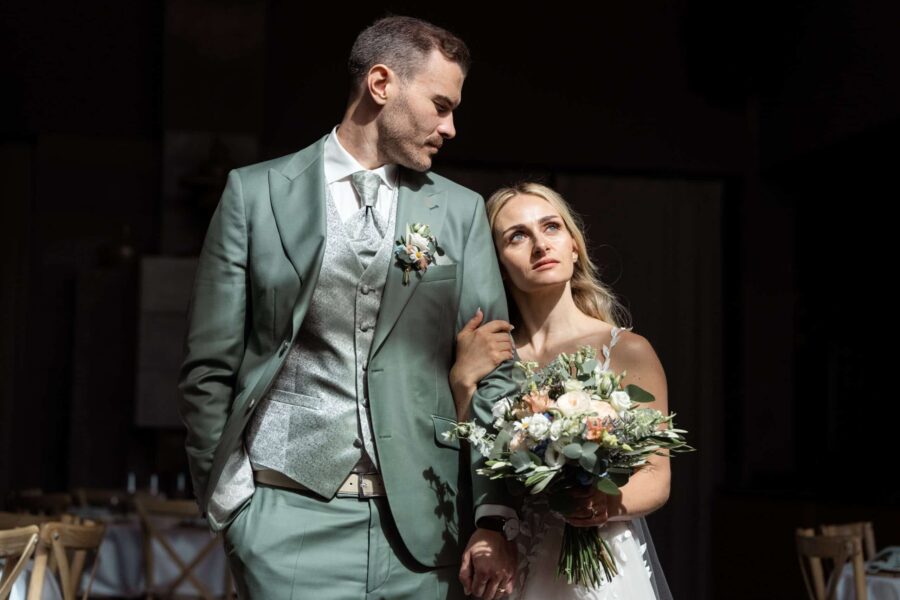 Brautpaar in eleganter Kleidung mit Blumenstrauß