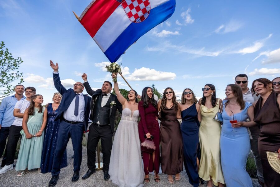 Hochzeitsgäste feiern mit Landesflagge im Freien