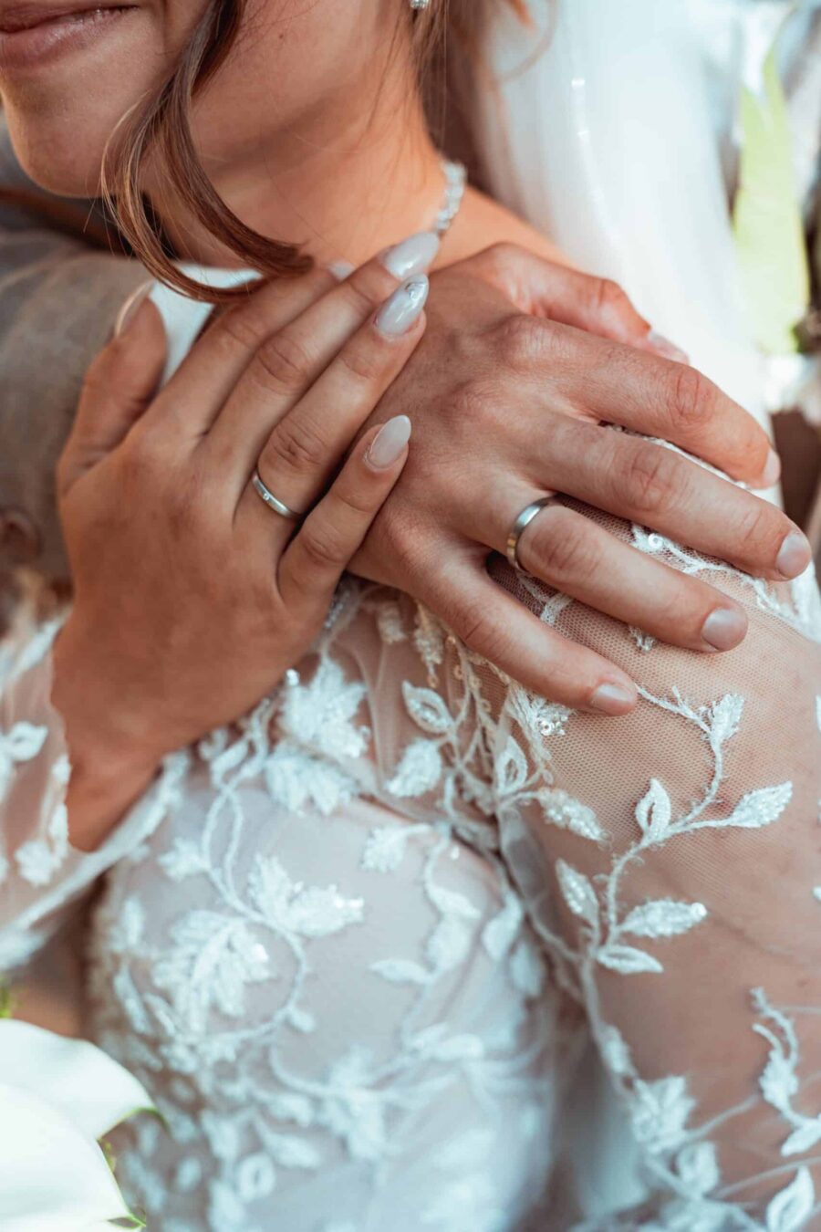 Nahaufnahme von Händen mit Eheringen und Hochzeitskleid
