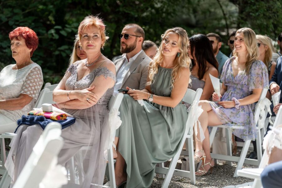 Gäste sitzen bei sonniger Hochzeit im Freien.