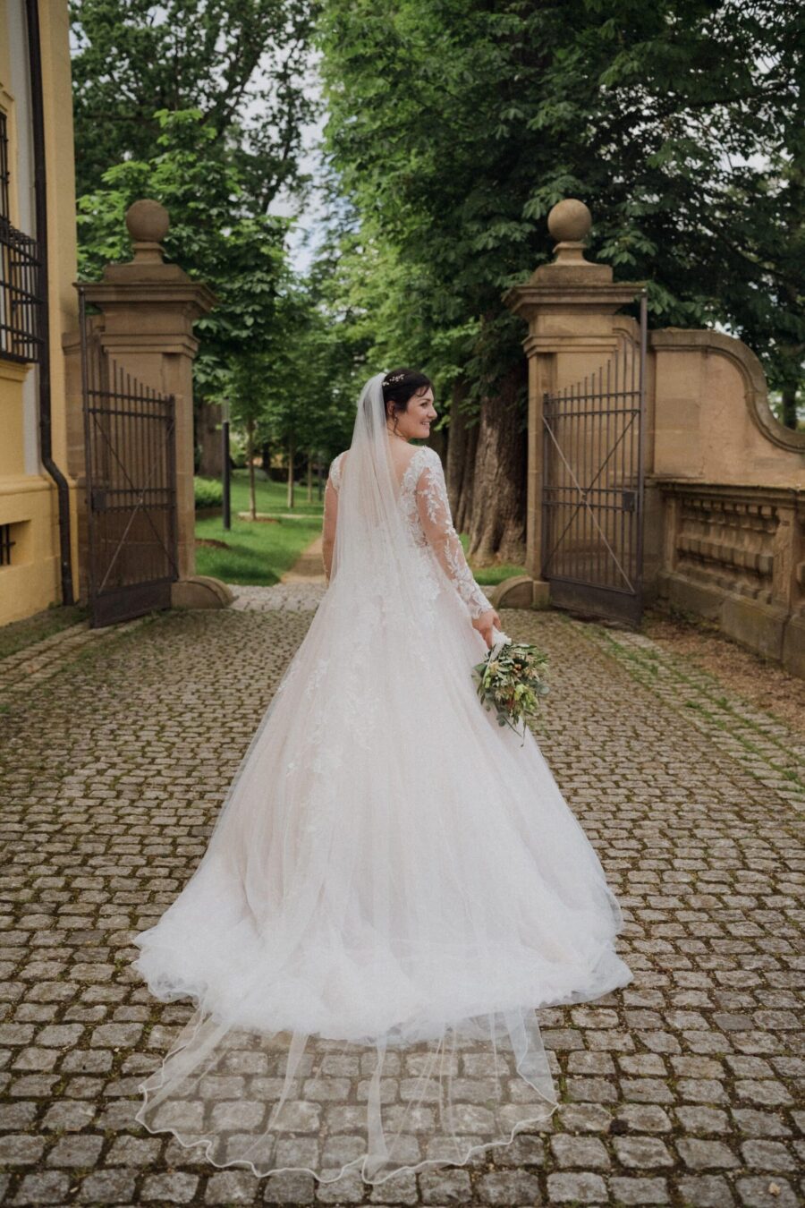 Braut im Garten mit Brautkleid und Blumenstrauß