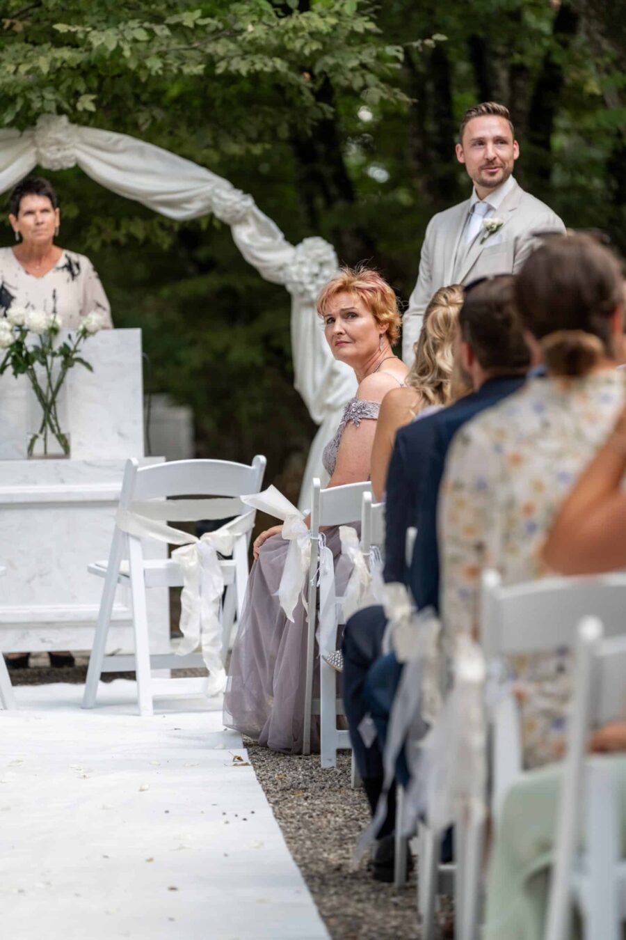 Hochzeitszeremonie im Freien mit Gästen und Traubogen