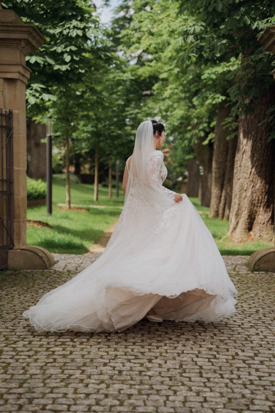 Braut im weißen Kleid auf einem Kopfsteinpflasterweg