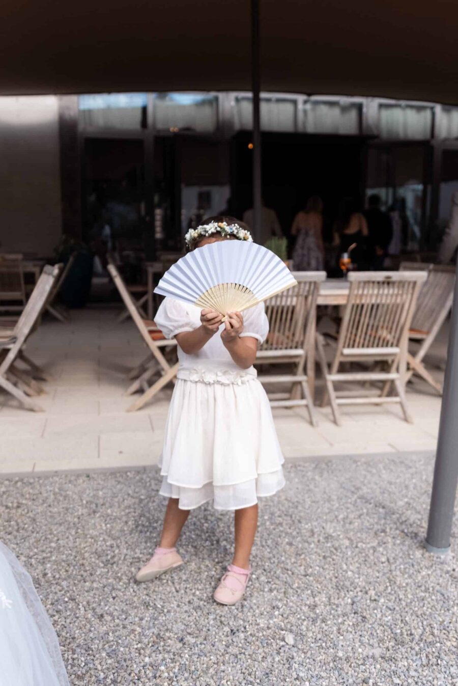 Blumenmädchen mit Fächer vor Hochzeitslokation.