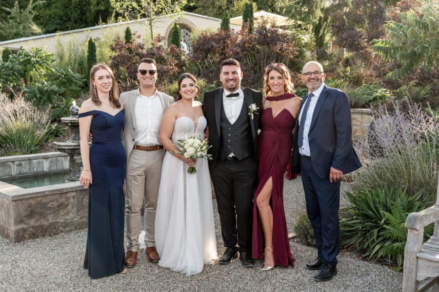 Brautpaar mit Gästen im Garten vor Brunnen