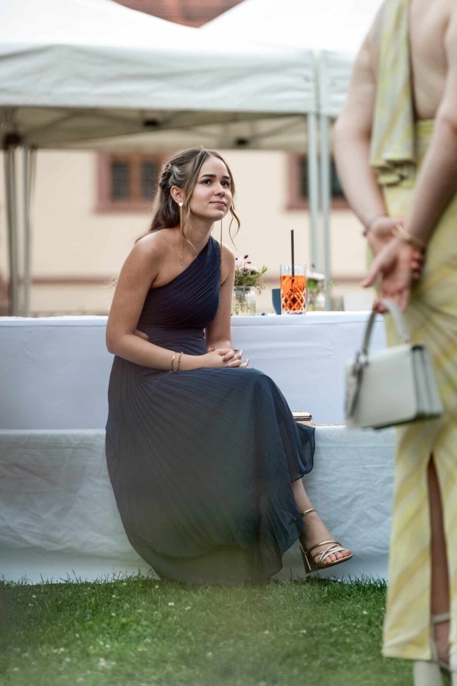 Gästin sitzt im eleganten Abendkleid bei Hochzeitsfeier.