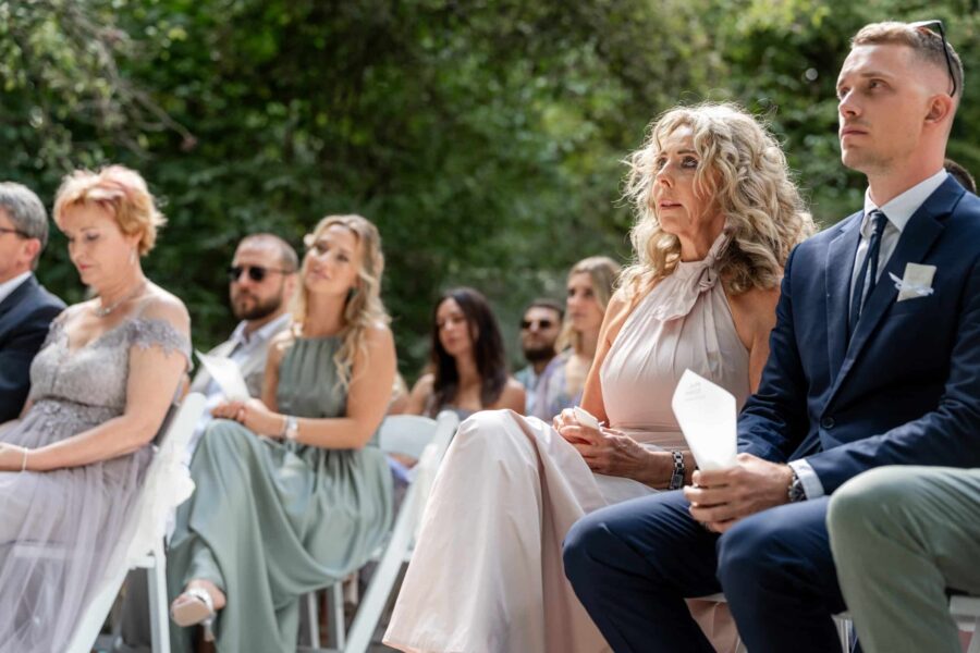 Gäste sitzen im Garten bei einer Trauungszeremonie.