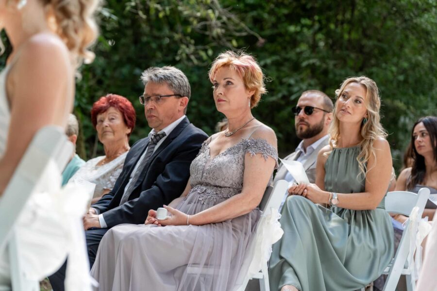 Gäste sitzen bei einer Trauungszeremonie im Freien.