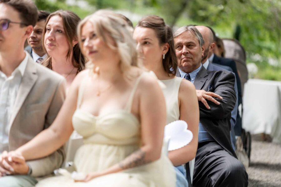 Gäste sitzen draußen bei Hochzeitszeremonie