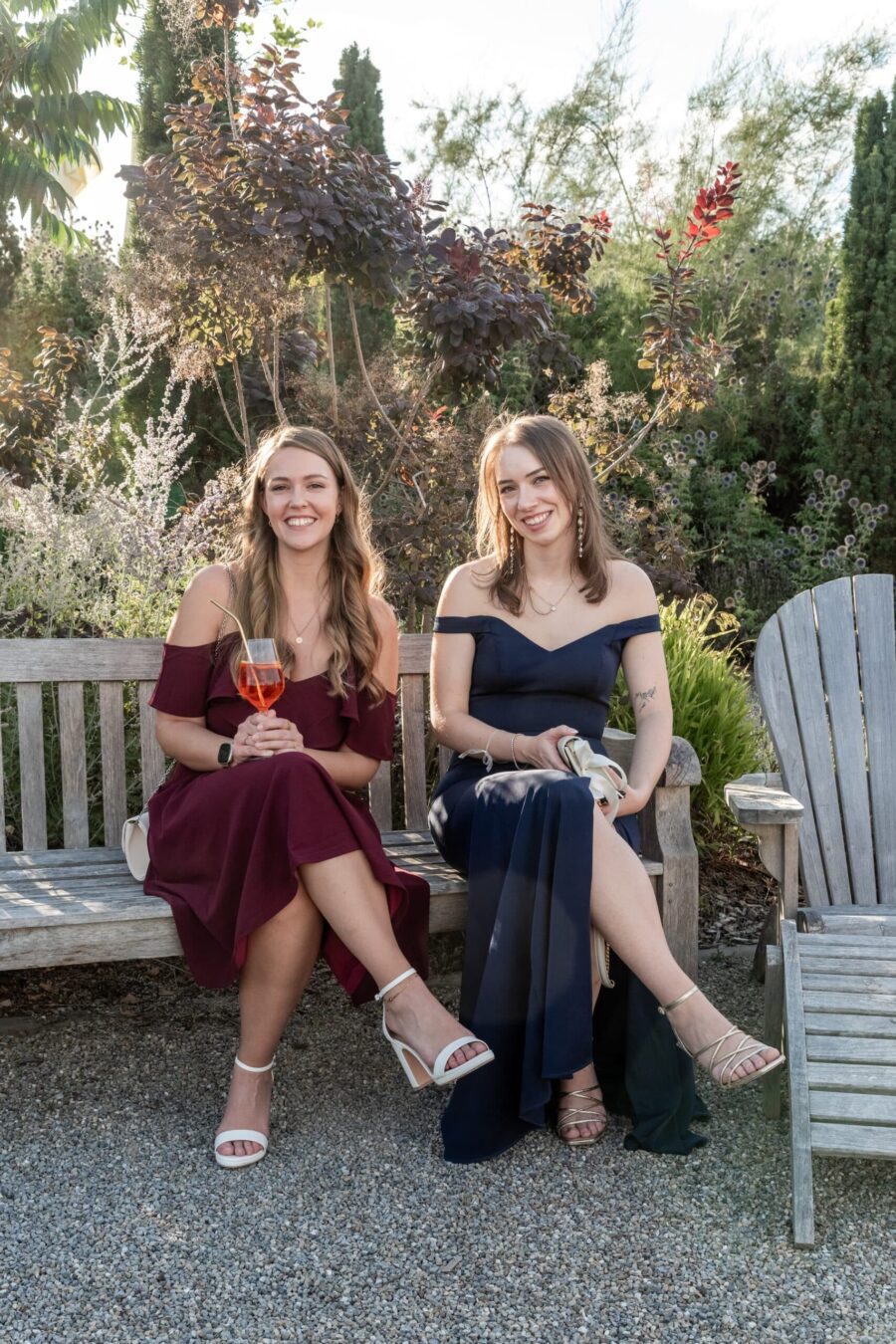 Gäste sitzen in schickem Garten auf Holzbänken