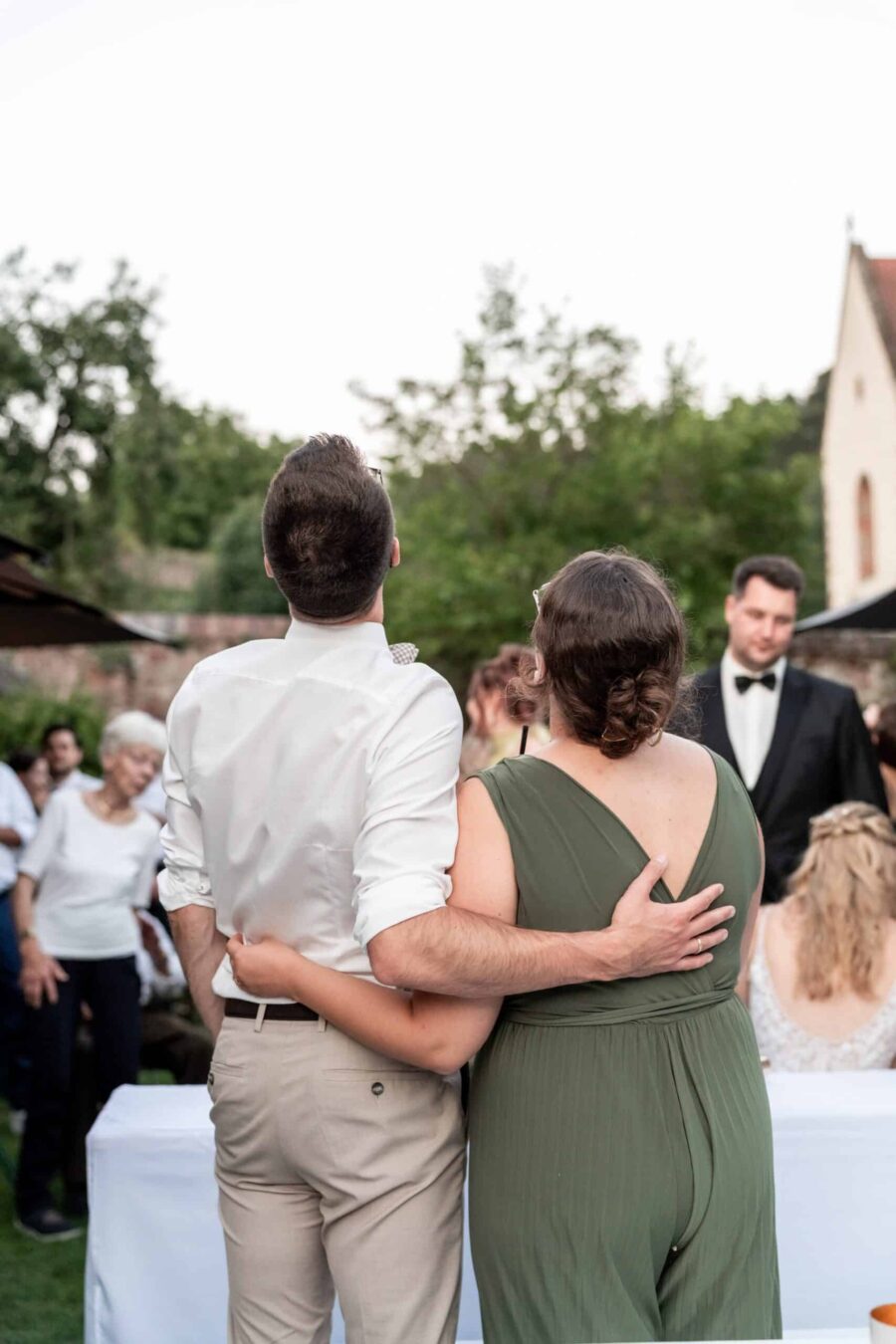Gäste feiern Hochzeit im Freien vor Kirche