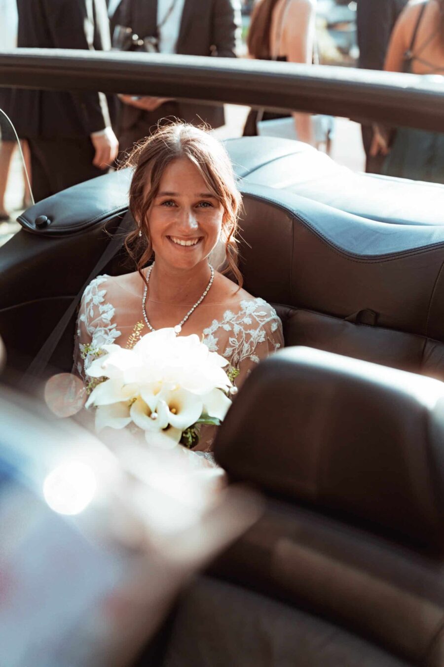 Braut mit Blumenstrauß im Auto