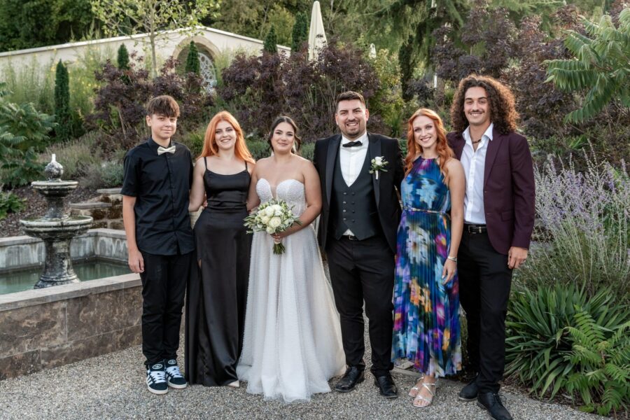 Brautpaar mit Gästen im Garten vor dem Brunnen