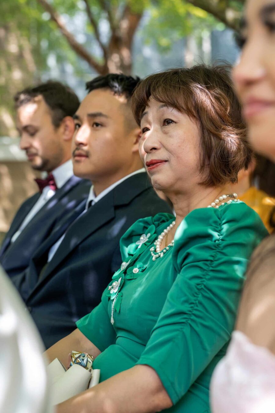 Hochzeitsgäste sitzen im grünen Außenbereich