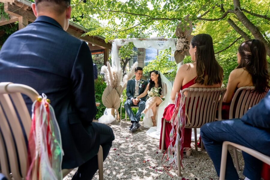 Hochzeitspaar unter Blumenbogen im Garten.