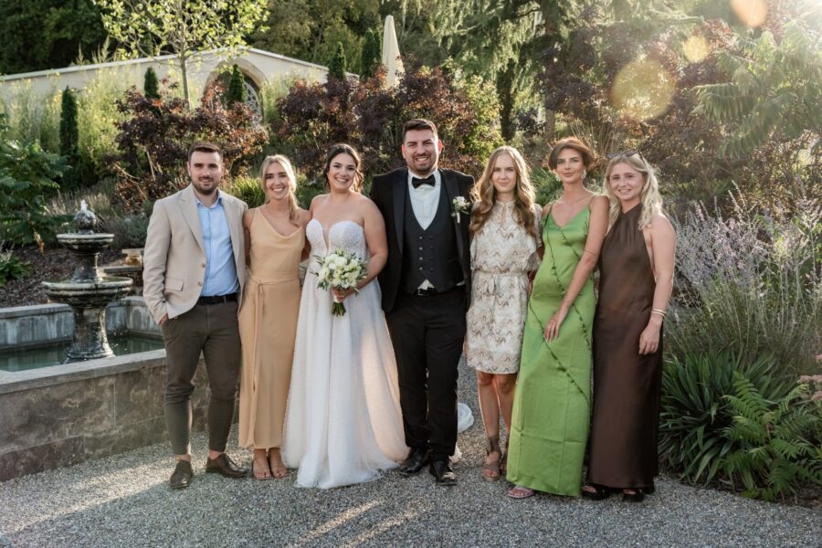 Brautpaar mit Gästen im Garten vor Brunnen