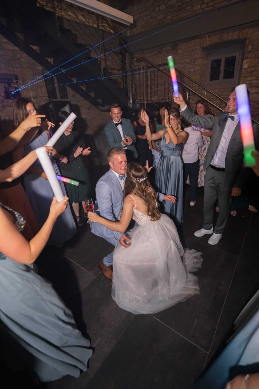 Hochzeitstanz mit Gästen und leuchtenden Stäben