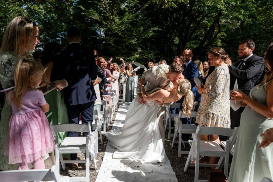 Brautpaar-Kuss im Freien vor applaudierenden Gästen