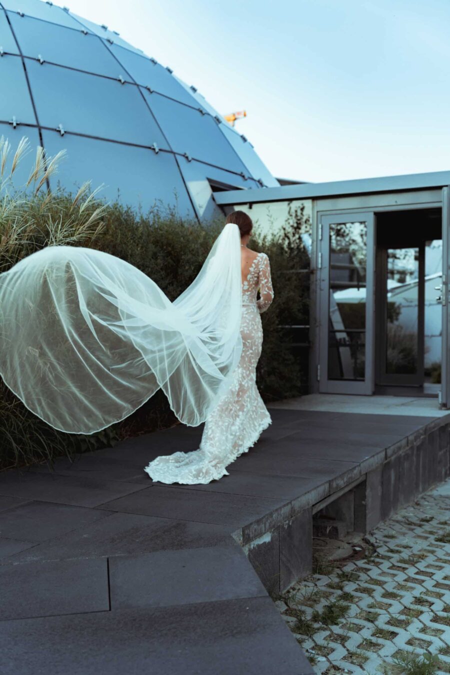 Braut mit Schleier vor moderner Location