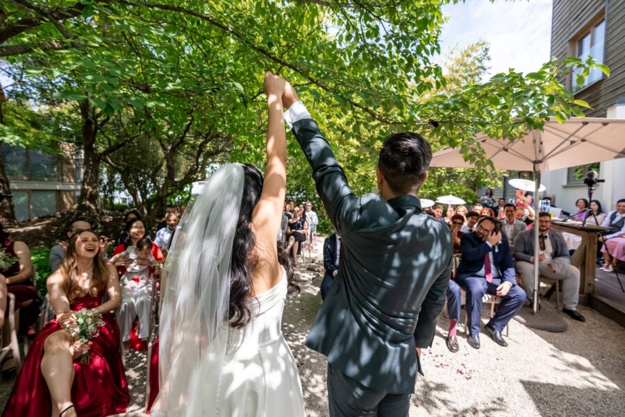 Brautpaar hebt Hände bei Sommerhochzeit im Garten