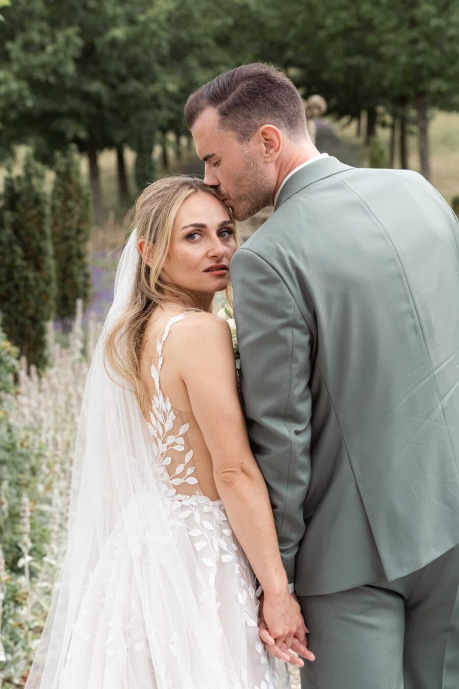 Brautpaar im Garten mit zärtlicher Geste
