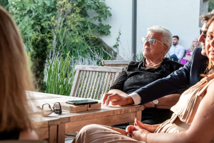 Gäste sitzen an Holztischen im Garten