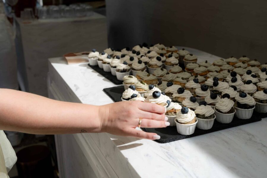 Hochzeit Villa Oriental | Editorial Summer Vibes & Live Cooking 126 Hand greift nach Cupcakes auf Hochzeitstisch