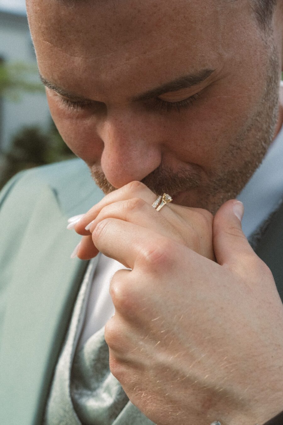Groom küsst Hand mit Ehering im Garten.