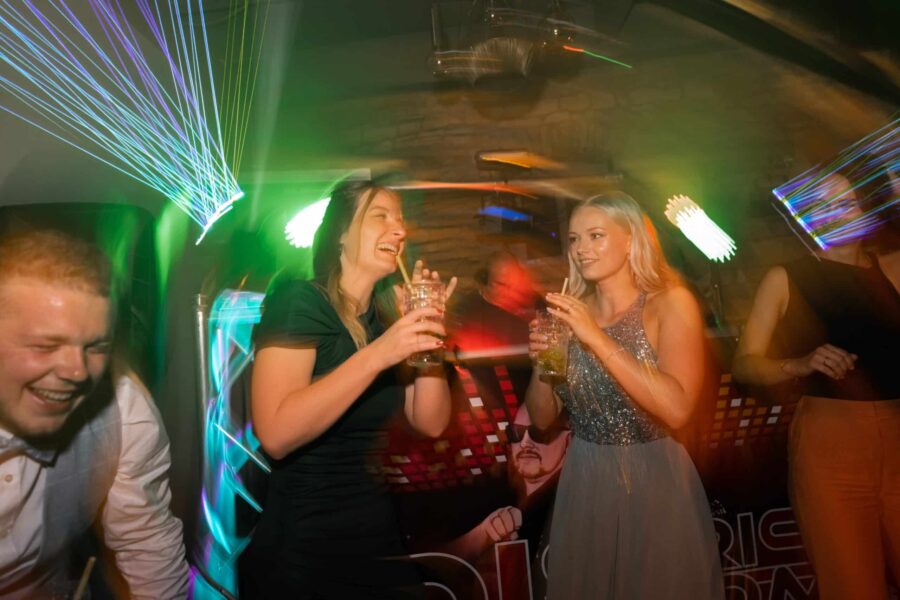 Hochzeitsfeier mit fröhlichen Gästen und Lichteffekten.