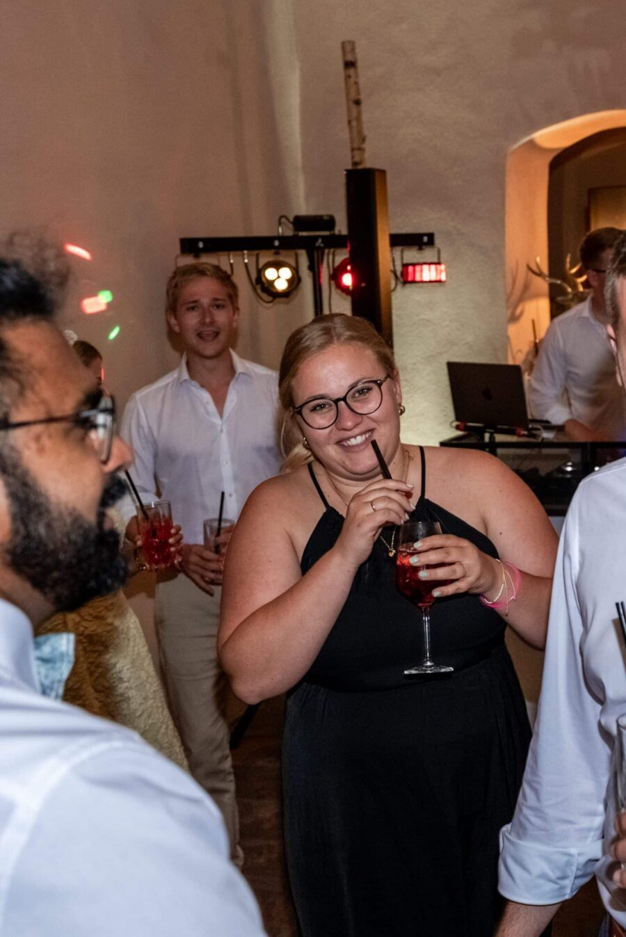 Gäste mit Cocktails auf Hochzeitsfeier drinnen