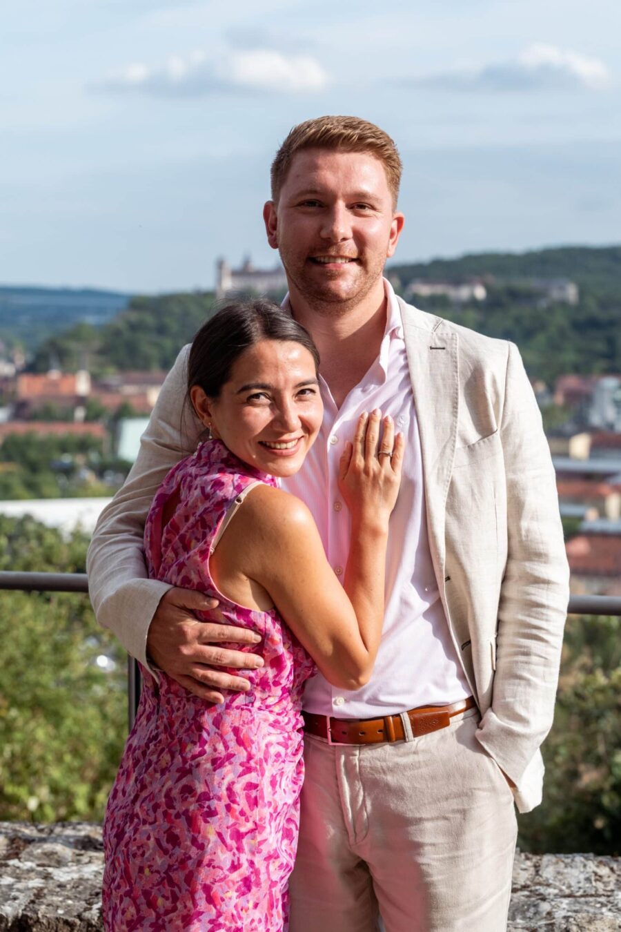 Hochzeit Steinburg Würzburg | Editorial Style & Party | Florian Knusper 158 Paar posiert lächelnd vor Stadtlandschaft