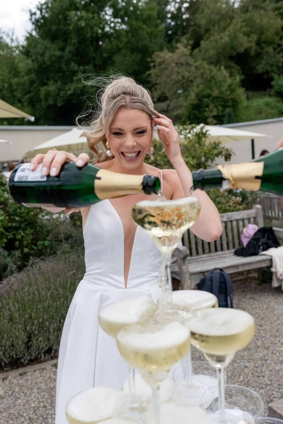 Braut füllt Champagnerturm im Garten.