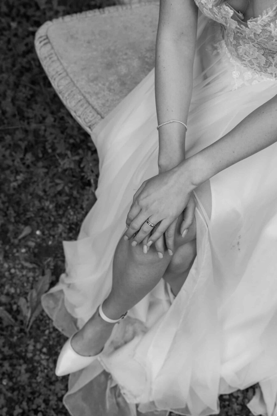 Braut in Hochzeitskleid auf steinerner Bank