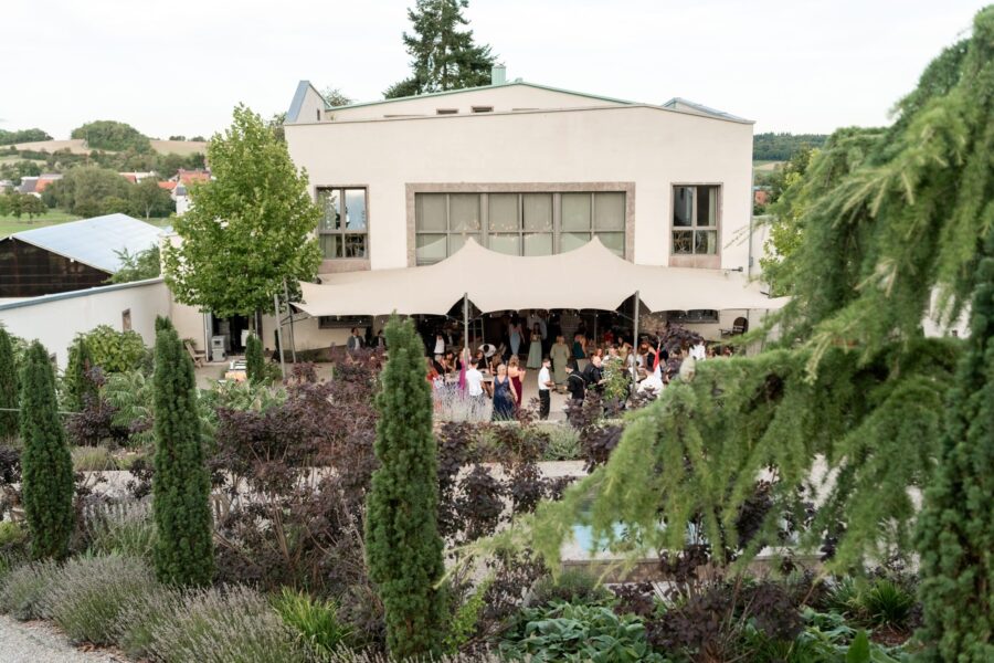 Hochzeitsfeier im Garten mit Gästen und Pavillon.