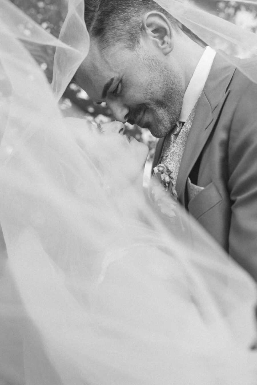 Brautpaar küsst sich unter Schleier im Garten