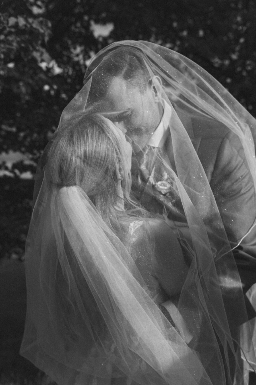 Brautpaar küsst sich unter funkelndem Schleier