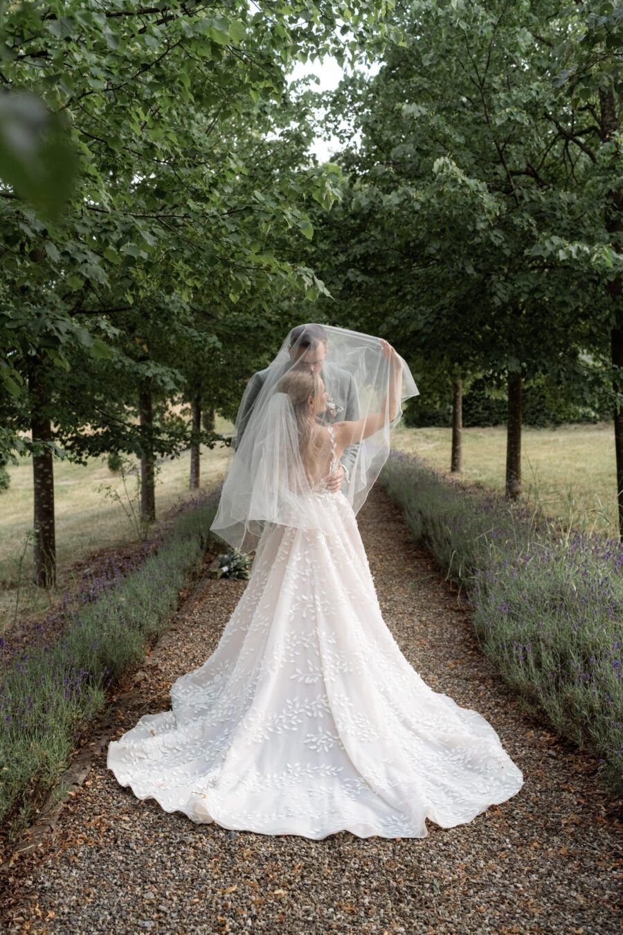 Brautpaar unter Schleier im Gartenweg