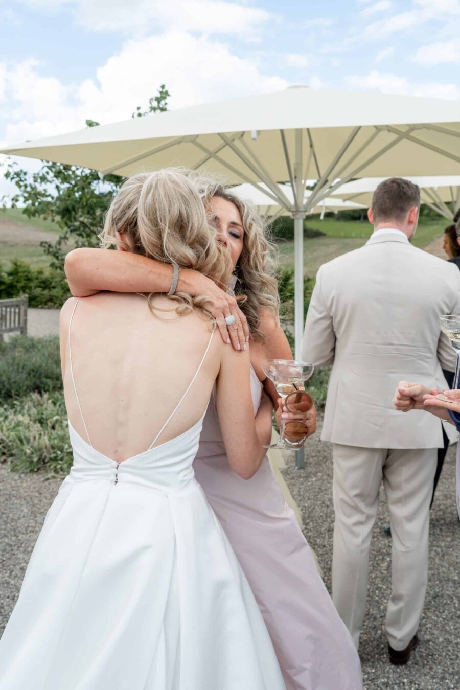 Umarmung unter Gästen im Garten bei Hochzeitsfeier