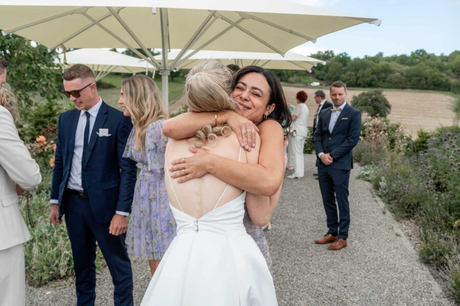 Umarmung unter Hochzeitsgästen im Garten.