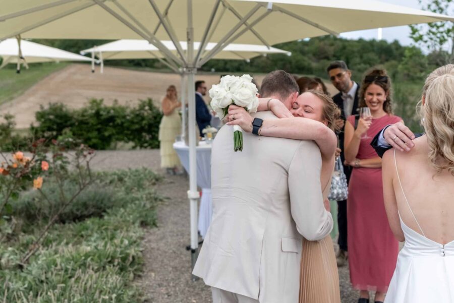 Hochzeitspaar umarmt sich im Garten unter Sonnenschirmen