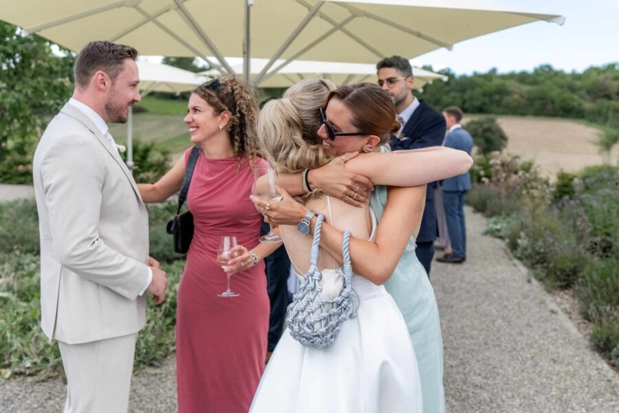 Gäste umarmen sich bei Hochzeitsfeier im Freien