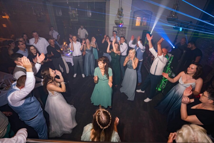 Hochzeitsgäste tanzen in beleuchtetem Saal