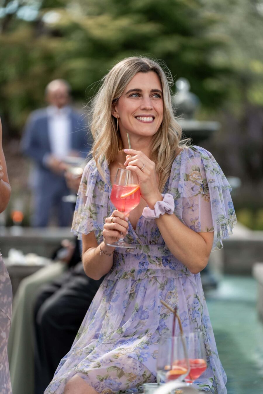 Gästin genießt Getränk bei Hochzeitsempfang im Freien