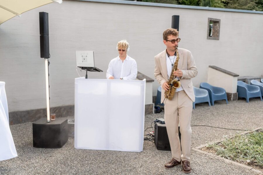 Musiker mit Saxophon und DJ auf Hochzeitsfeier im Freien.