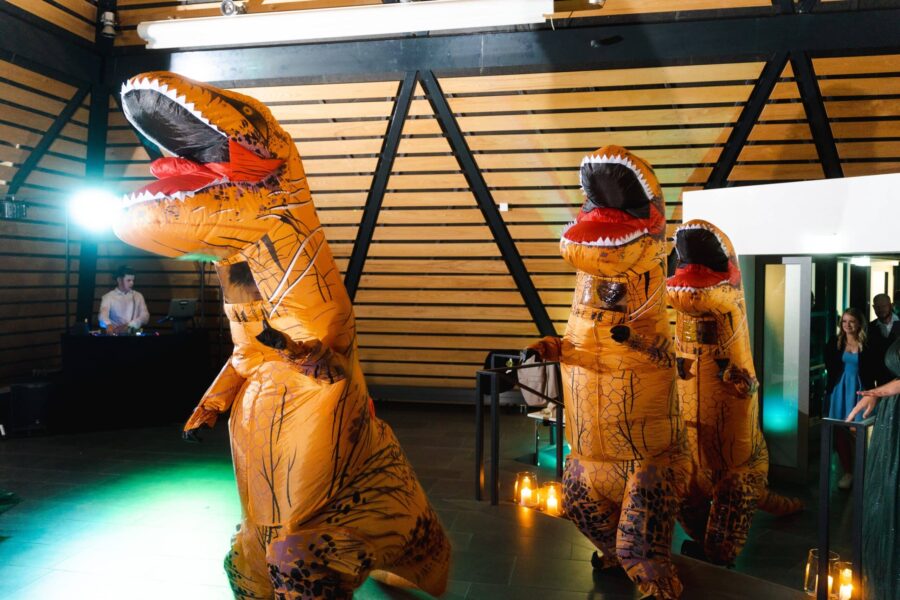 Tanzende Gäste in Dino-Kostümen auf Hochzeitsfeier