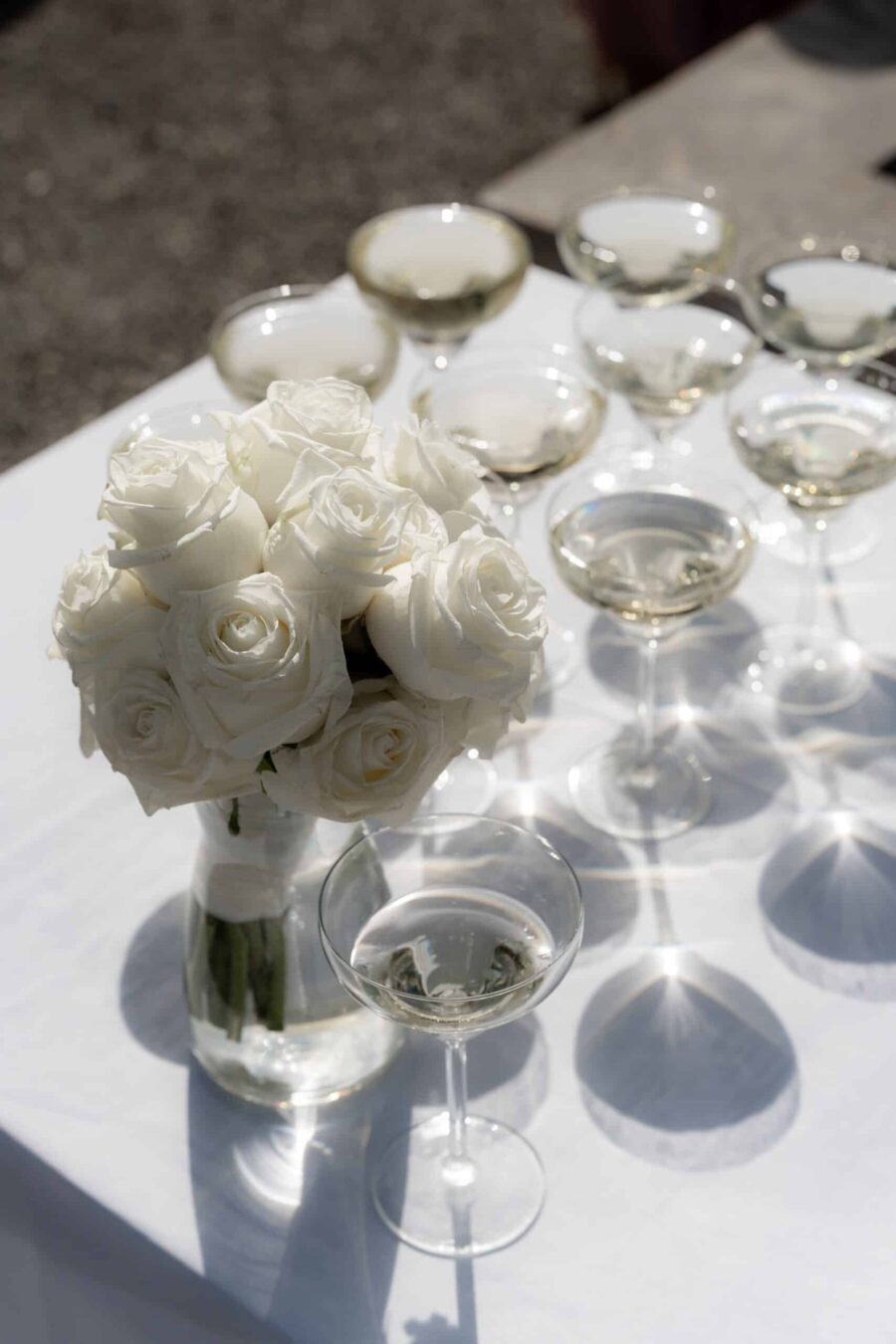 Weiße Rosen und Sektgläser auf Hochzeitstisch
