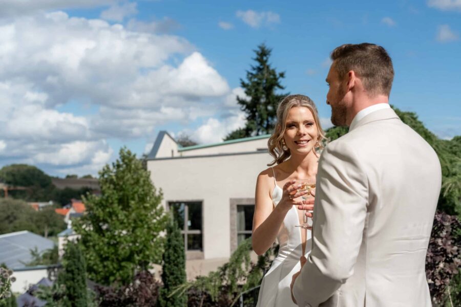 Brautpaar mit Sekt im Garten bei Sonnenschein